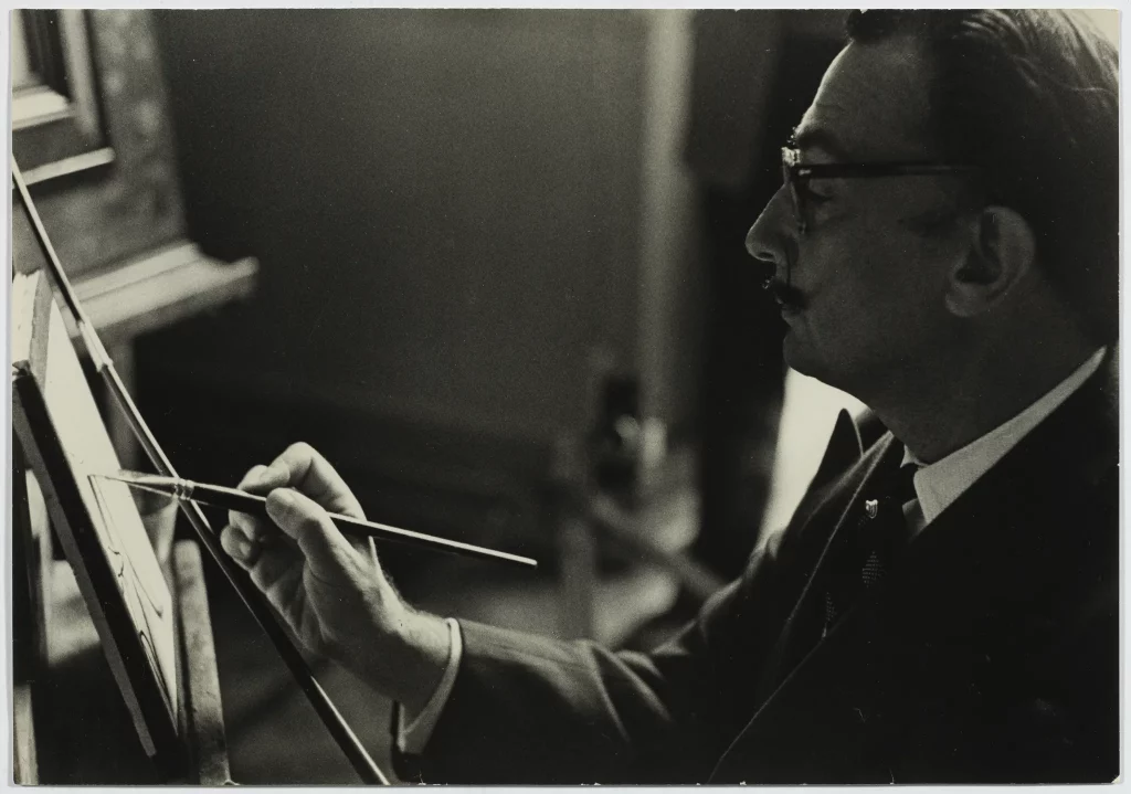 Salvador Dalí peignant sa version de <em>La Dentellière</em> de Johannes Vermeer au musée du Louvre de Paris, 1954 
Photo R. Descharnes/ © Descharnes & Descharnes sarl 2024 Droits d’image de Salvador Dalí réservés. Fundació Gala-Salvador Dalí, Figueres, 2024